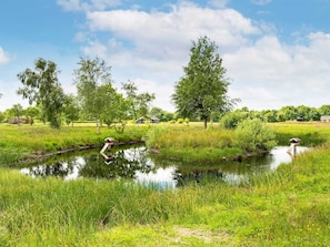 A serene landscape with a pond, trees, and a house in the background. - 5 Star Holiday Home in Ansager (Ansager)
