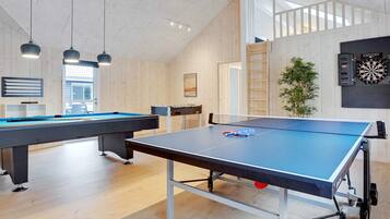 Een kamer met een tafeltennistafel, een pooltafel en een dartbord.