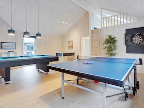 A room with a ping pong table, a pool table, and a dartboard.