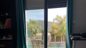 Un dormitorio con una cama grande, vistas a una piscina y mobiliario exterior, además de una estantería.