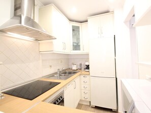 A compact kitchen with white cabinets, a stainless steel range hood, a built-in oven, a sink, and a refrigerator. - Del Parque Flats Catedral Exclusive: Central Apartment Near Museums & Beach à Málaga (Málaga)