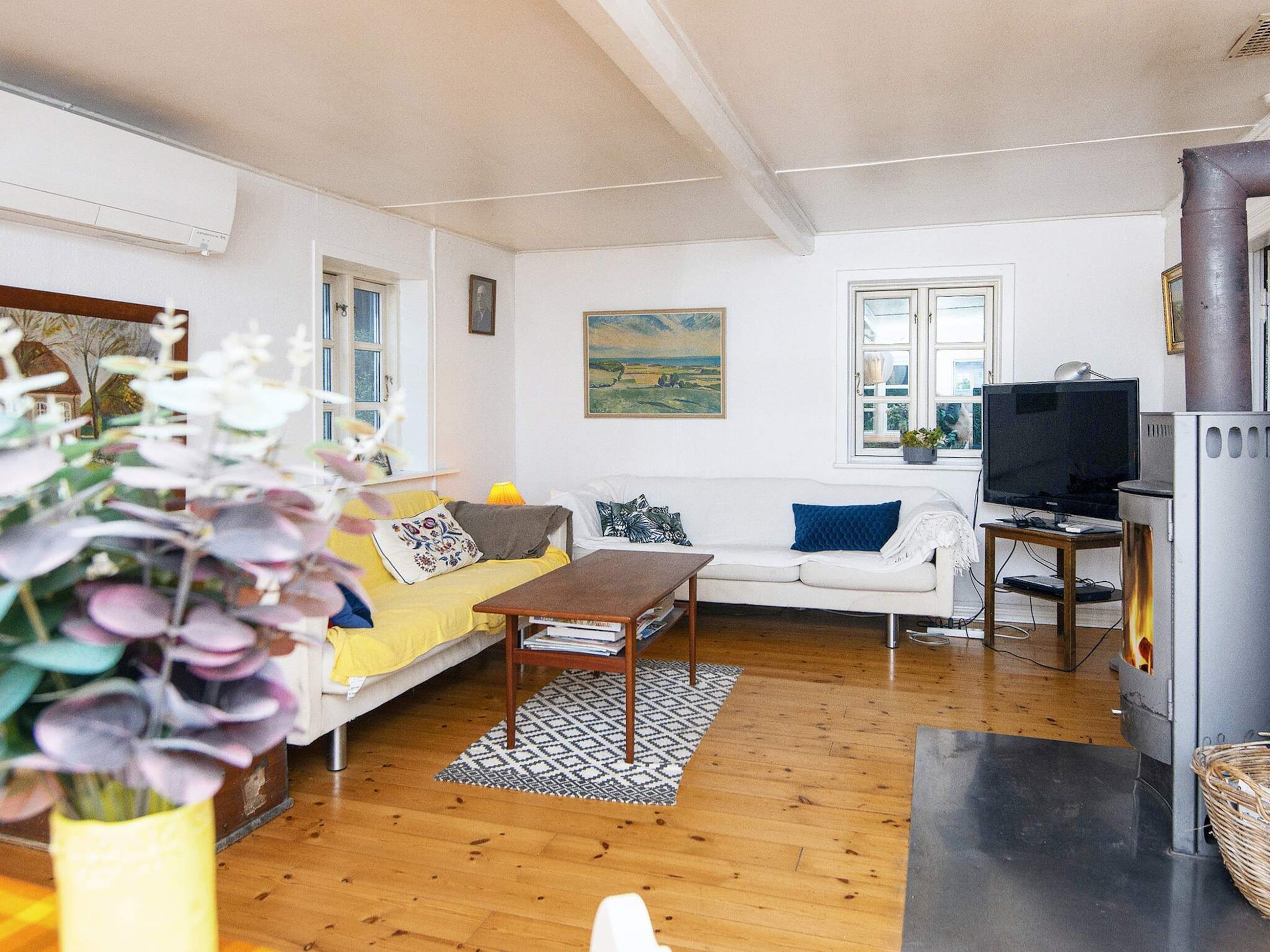 A living room with a sofa, a coffee table, a television, and a fireplace.