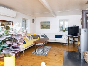 A living room with a sofa, a coffee table, a television, and a fireplace. - 5 Person Holiday Home in Skanderborg (Skanderborg)