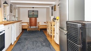 A compact kitchen with a refrigerator, sink, and wooden cabinets. There are two beds with wooden frames and a painting on the wall. - 5 Person Holiday Home in Skanderborg (Skanderborg)