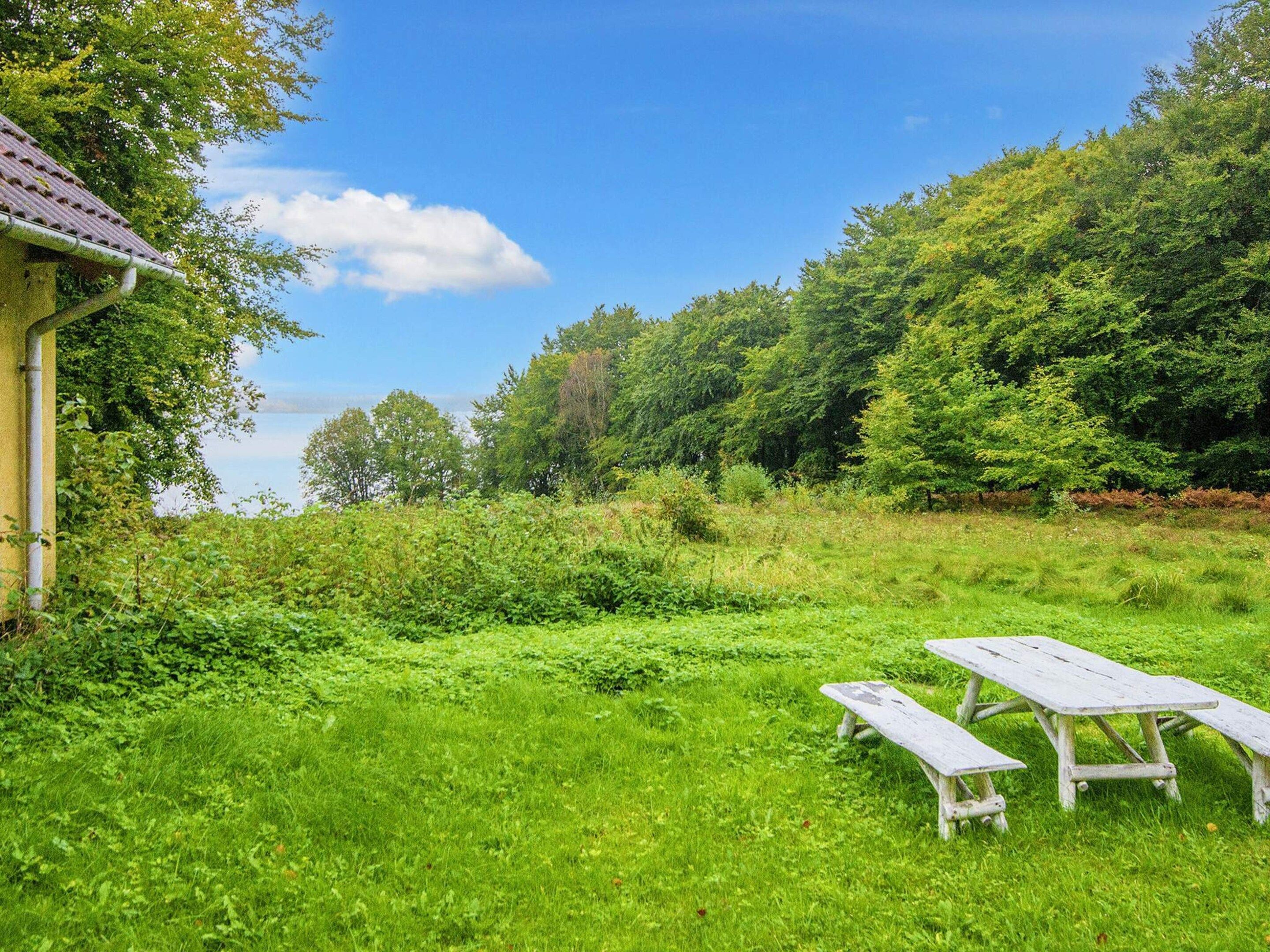 Ett grönområde med två vita picknickbord och en byggnad med ett rött tak.