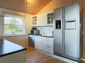 A modern kitchen with white cabinetry, a stainless steel refrigerator, a microwave, and a dishwasher.