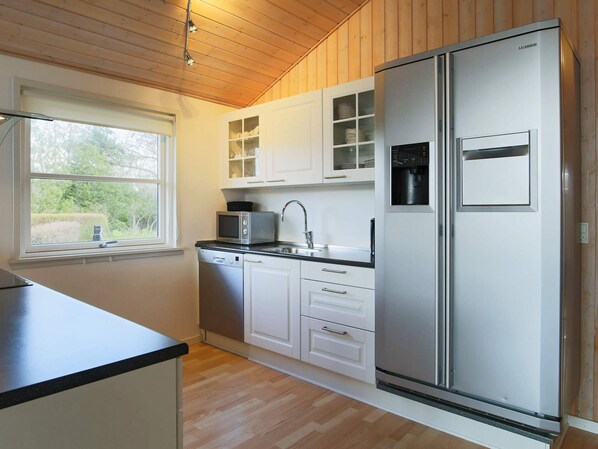 A modern kitchen with white cabinets, a stainless steel refrigerator, a microwave, and a dishwasher.