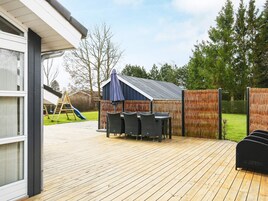 A wooden deck with outdoor furniture, a covered seating area, and a play structure in the background.