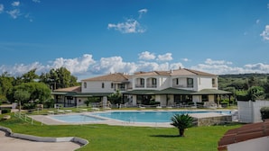 A resort with a large swimming pool, multiple buildings with balconies, and lush greenery. - La Smeraldina Resort (Santa Teresa di Gallura)