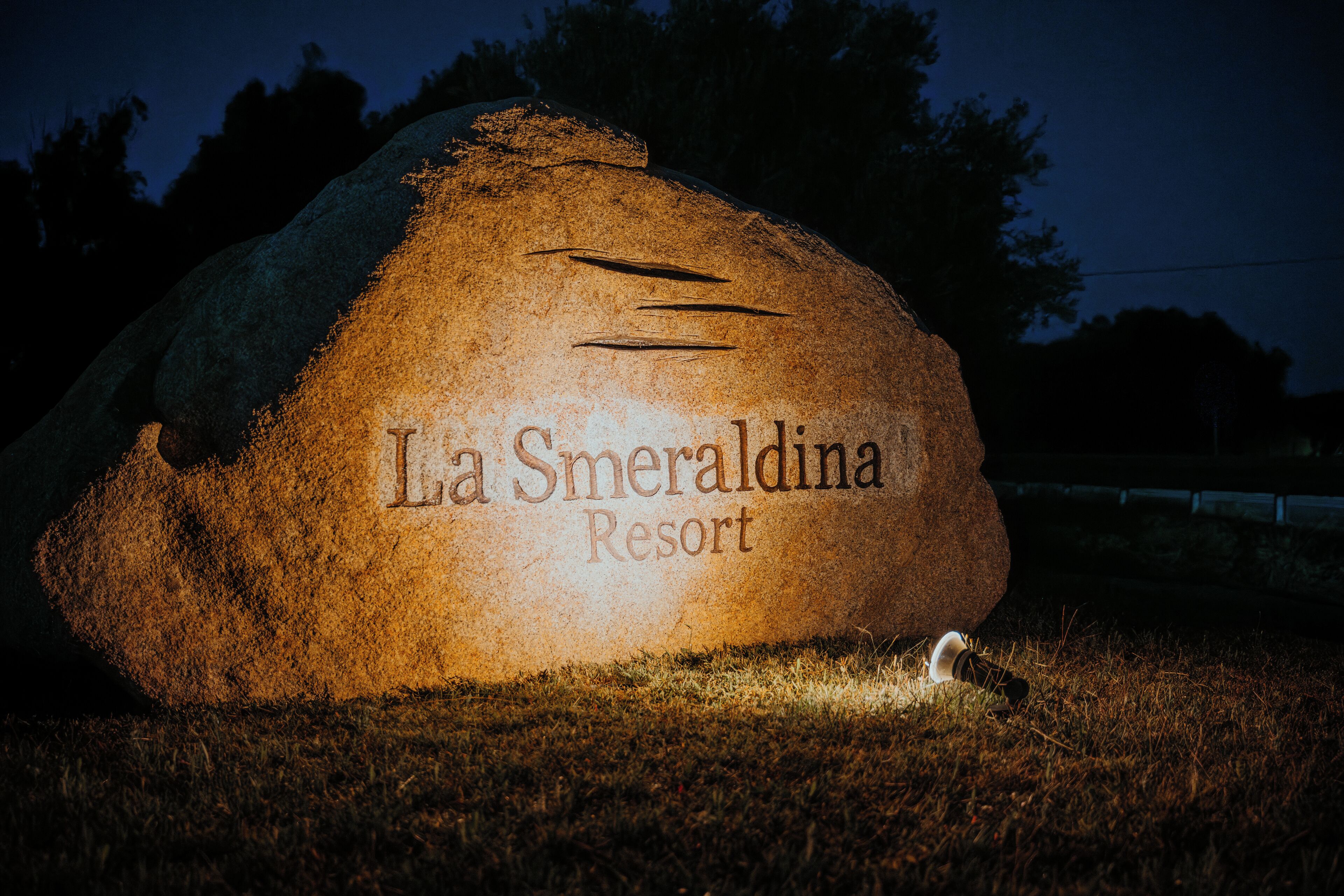 A large rock with the inscription "La Smeraldina Resort" at night.