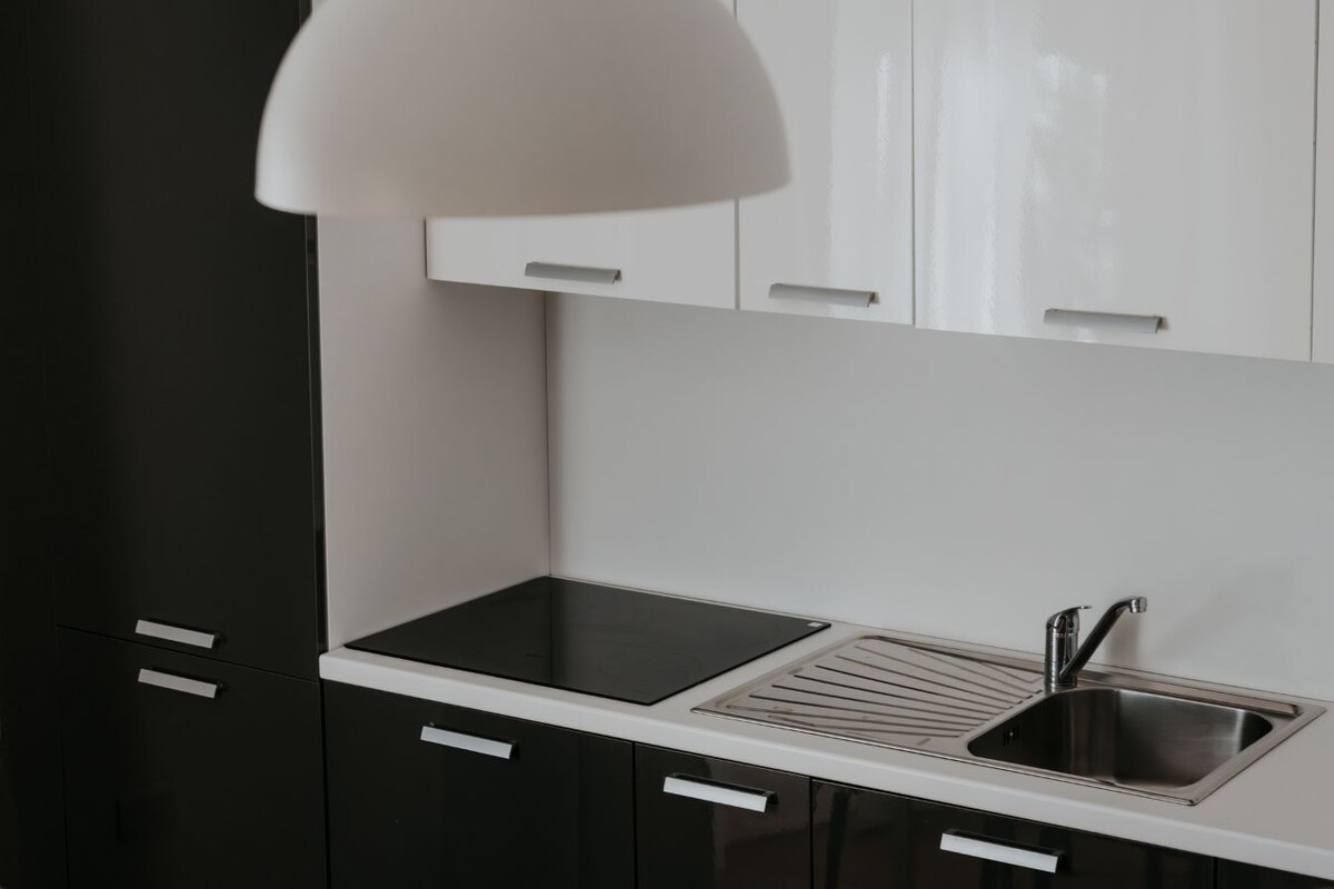 A modern kitchen with a black countertop, stainless steel sink, and white cabinets.