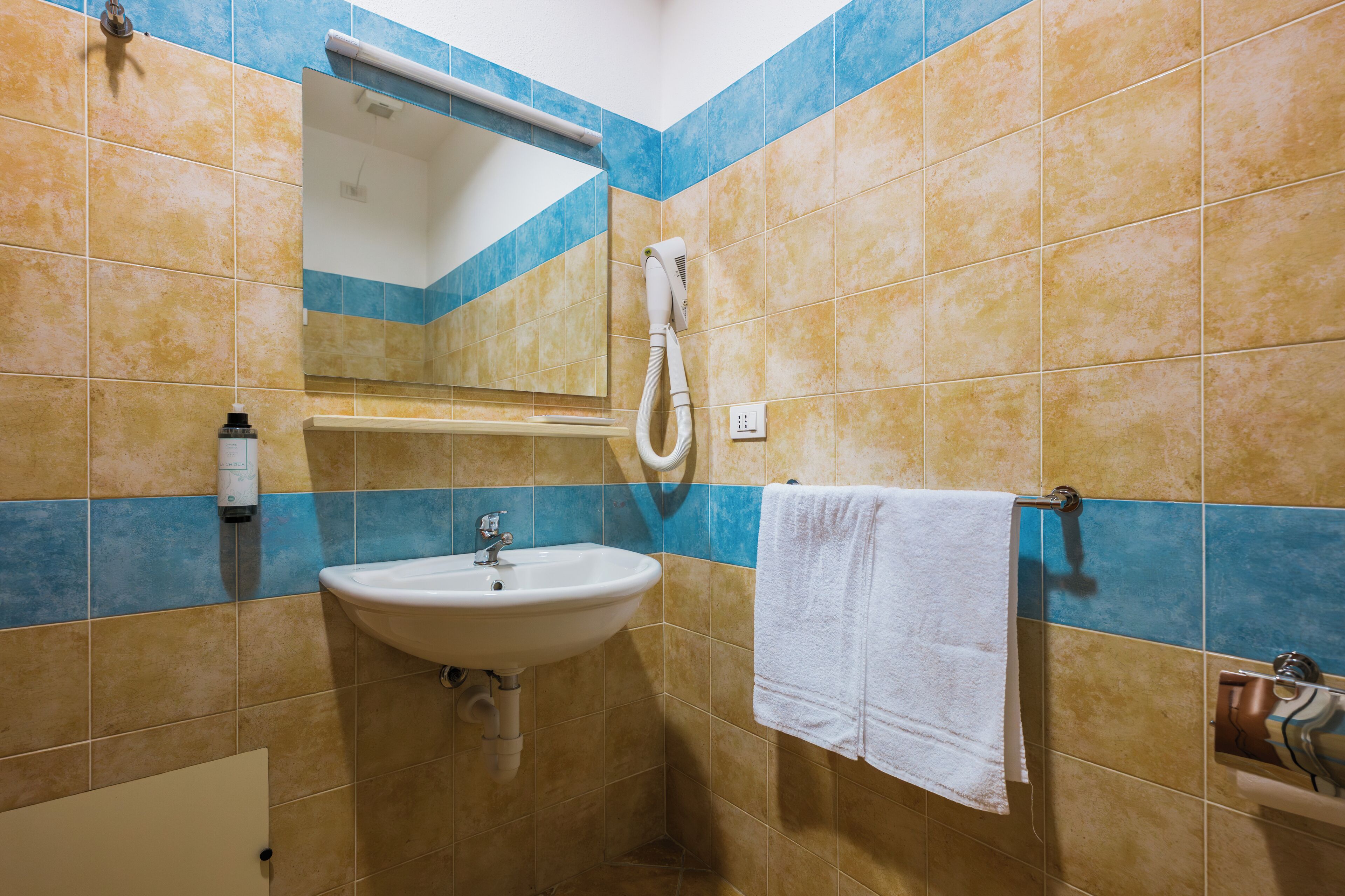 Un baño con lavamanos, espejo, toallero y ducha.