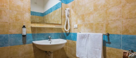 A bathroom with a sink, mirror, towel rack, and shower.