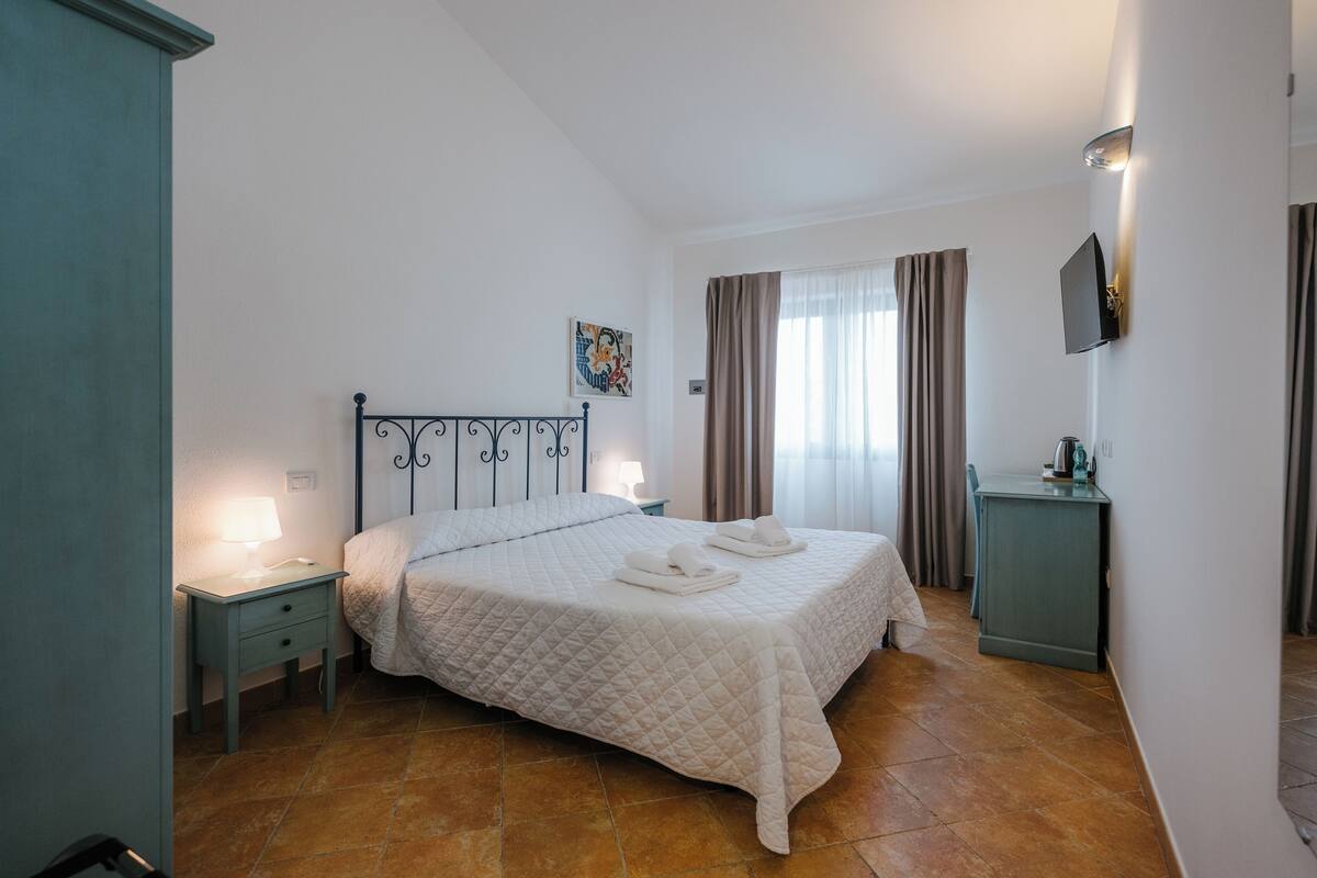 A bedroom with a bed, nightstand, and a TV mounted on the wall.