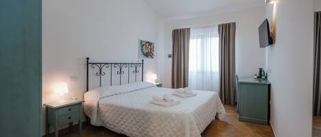 A bedroom with a bed, nightstand, and a TV mounted on the wall.