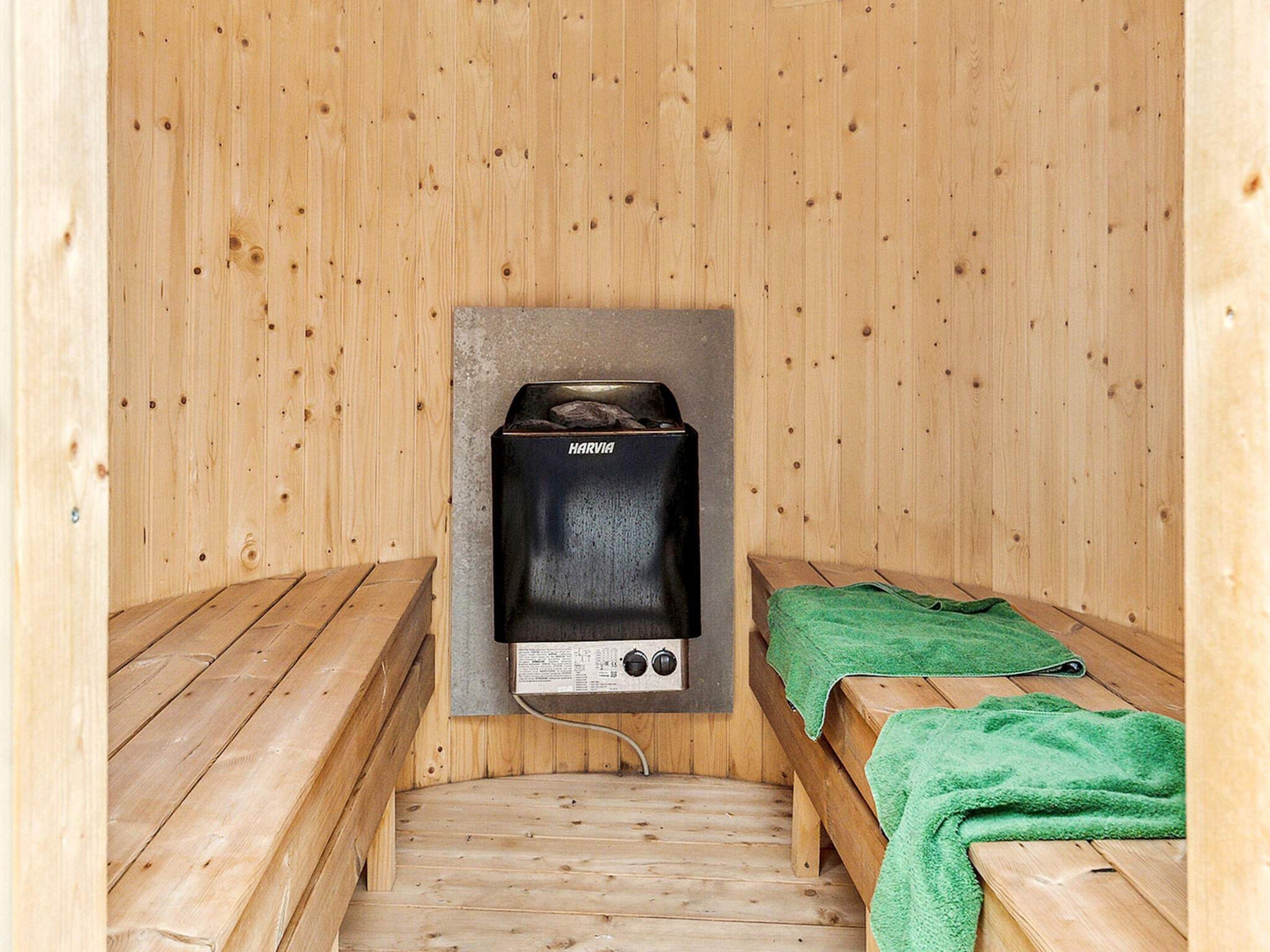 A sauna room with wooden benches and a Harvia sauna unit.