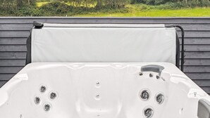 Uma banheira de hidromassagem com quatro jatos, um painel de controle e uma tampa.