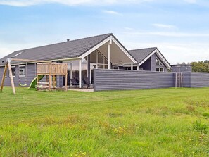 Una propiedad residencial con un patio cubierto, una estructura de juego de madera y un patio cercado.