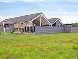 A residential property with a covered patio, a wooden play structure, and a fenced yard.