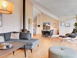 Un amplio salón con un sofá moderno, una mesa de comedor y una chimenea.
