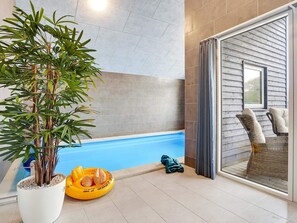 Zona de piscina con una planta en maceta, un flotador amarillo y una silla de mimbre.