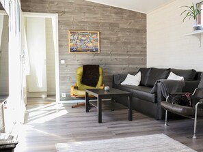 Ein modernes Wohnzimmer mit einer Couch, einem Sessel, einem Couchtisch und einem Bild an der Wand.