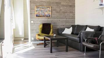 A modern living room with a sofa, a chair, a coffee table, and a painting on the wall.