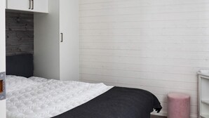 A bedroom with a bed, a wardrobe, a bedside table, and a pink ottoman. - 6 Person Holiday Home in Saffle (Saffle)