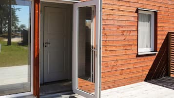 Una cabaña de madera con un patio exterior accesible mediante un gran ventanal corredizo.