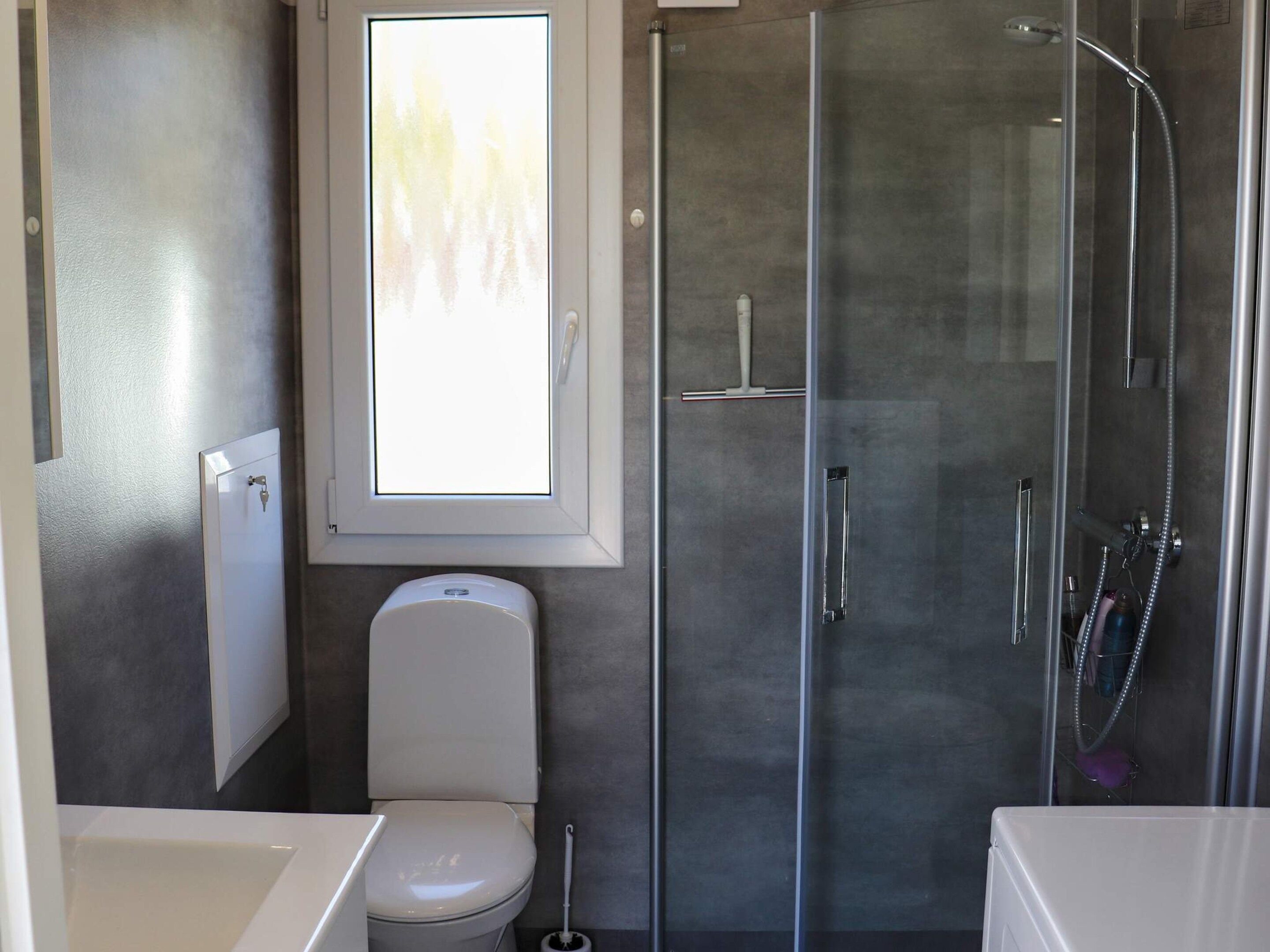 Ein Badezimmer mit Toilette, Duschkabine und Fenster.