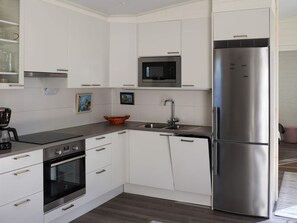 A modern kitchen with white cabinetry, a stainless steel refrigerator, a microwave, and a coffee maker. - 6 Person Holiday Home in Saffle (Saffle)