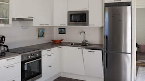 A modern kitchen with white cabinets, a stainless steel refrigerator, a built-in microwave, and a coffee maker. - 6 Person Holiday Home in Saffle (Saffle)
