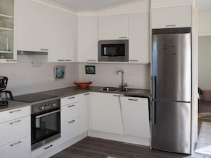 A modern kitchen with white cabinets, a stainless steel refrigerator, a built-in microwave, and a coffee maker. - 6 Person Holiday Home in Saffle (Saffle)