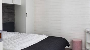 A bedroom with a bed, a wardrobe, a bedside table, and a pink stool.