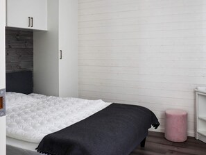 A bedroom with a bed, a wardrobe, a bedside table, and a pink stool. - 6 Person Holiday Home in Saffle (Saffle)