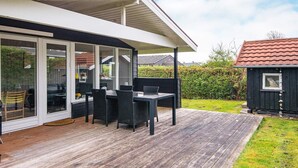 A modern house with a covered patio, a dining area with outdoor furniture, and a small shed in the yard. - 4 Person Holiday Home in Hejls (Hejls)