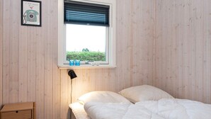 A bedroom with a bed, a bedside table, a lamp, and a window with a view of greenery. - 4 Person Holiday Home in Hejls (Hejls)