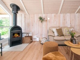 Una sala de estar acogedora con una estufa de leña, un sofá cómodo y una mesita con un jarrón de flores.