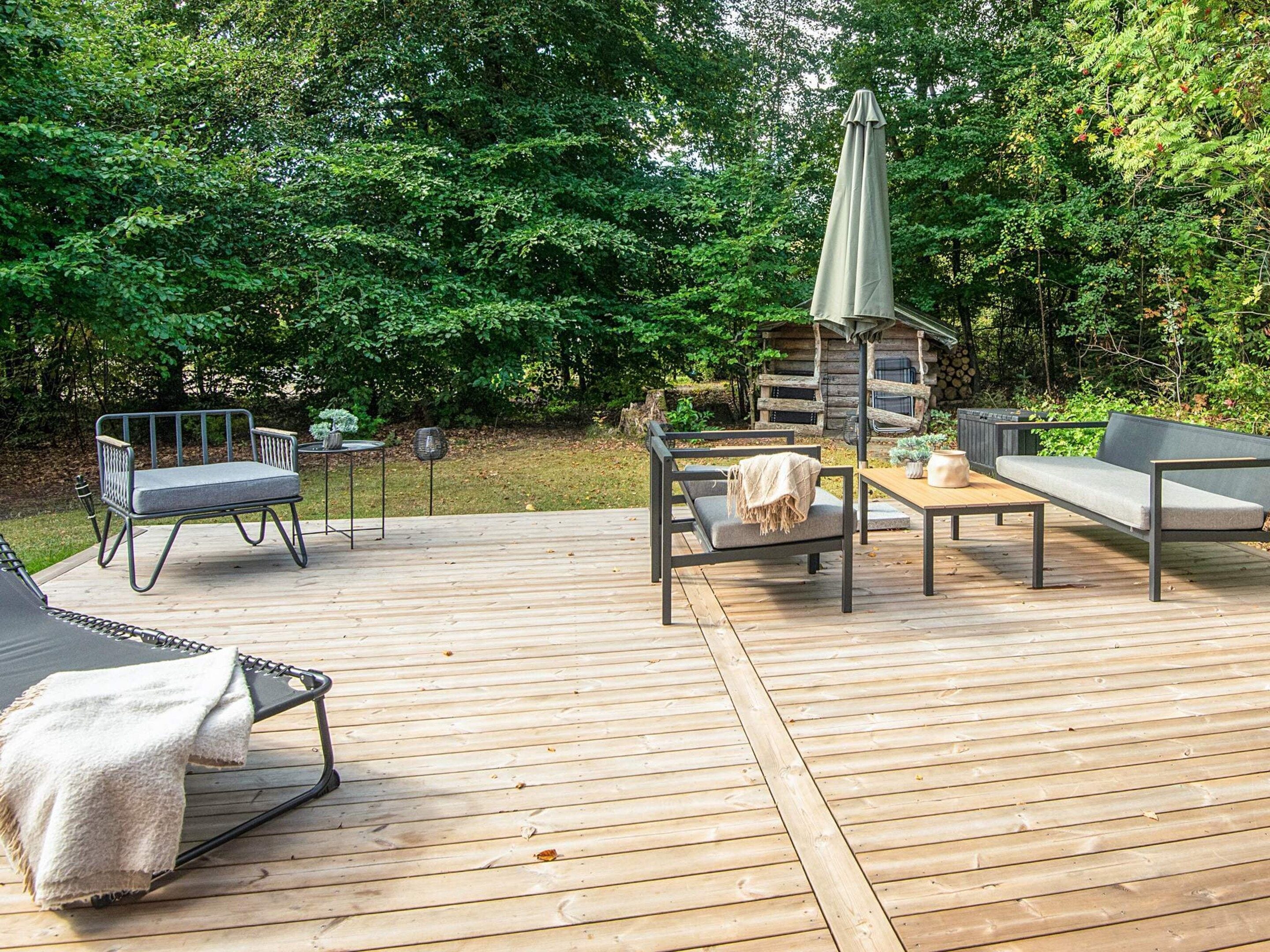 An outdoor deck with a dining table, chairs, and a lounge chair.