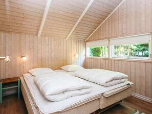 A wooden-paneled room with a bed, a bench, and a window.