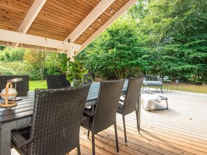An outdoor patio with a wooden deck, wicker furniture, and a table with a lamp.