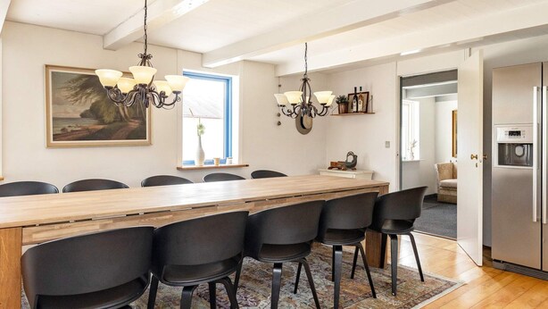 Un comedor con una larga mesa de madera, sillas negras y dos candelabros.