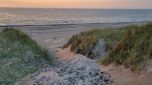 Una playa con dunas de arena y vistas al océano.