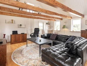 A living room with a leather sofa, a wooden coffee table, and a patterned rug.