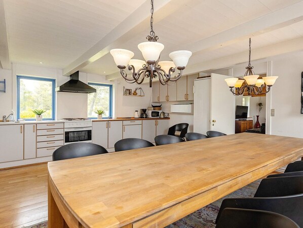 A modern kitchen with a wooden dining table, black chairs, and pendant lighting. - 12 Person Holiday Home in Thisted (Frøstrup)