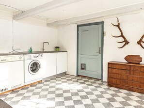 Une buanderie équipée d’un lave-linge, d’un évier et d’une porte avec une petite fenêtre.
