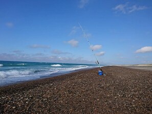 A fishing rod on a pebbly beach with the ocean in the background. - 12 Person Holiday Home in Thisted (Frøstrup)