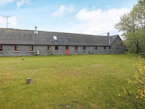 A large, single-story building with a corrugated metal roof, multiple windows with red frames, and a grassy yard in front. - 12 Person Holiday Home in Thisted (Frøstrup)
