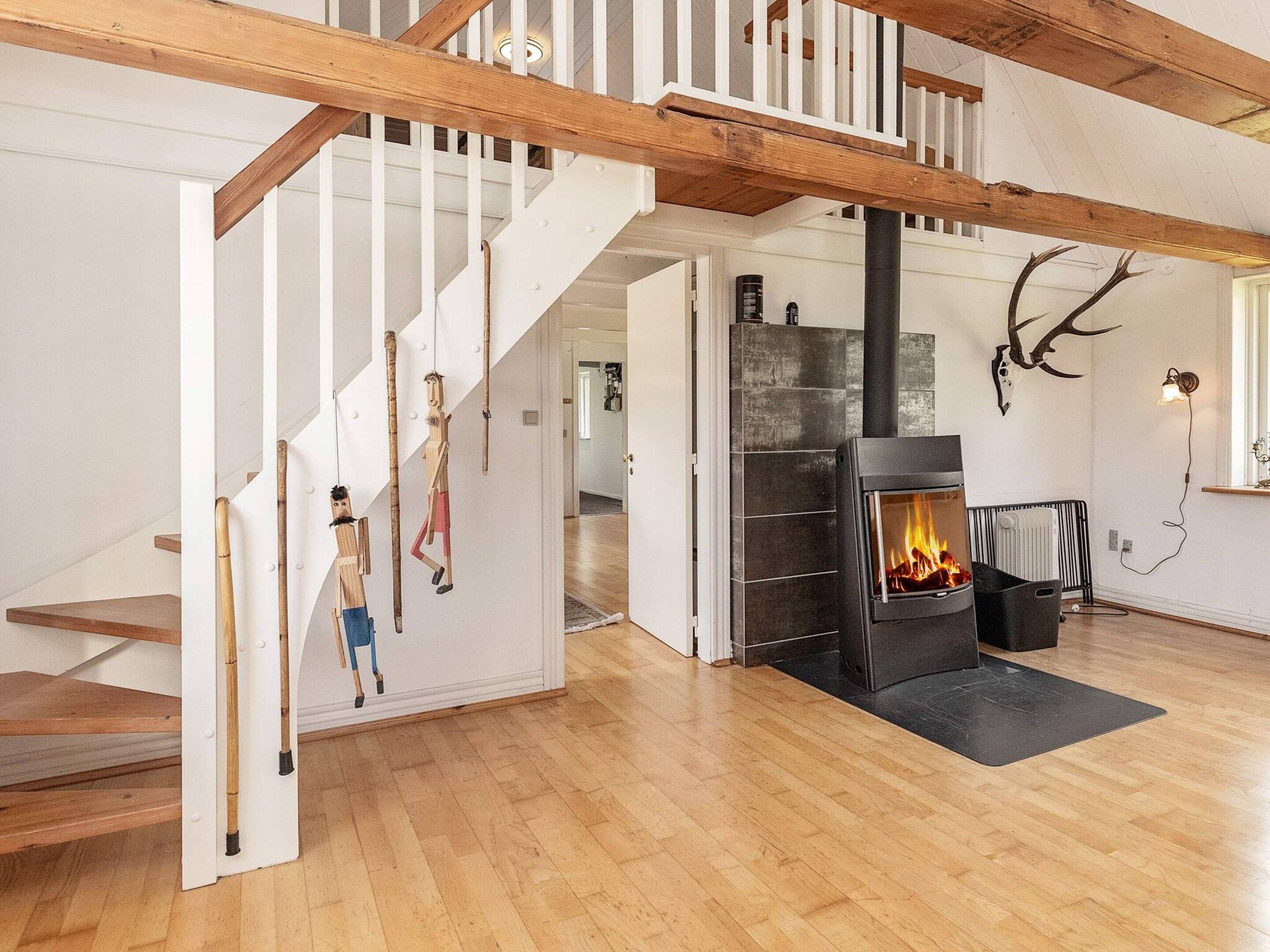 A modern interior with a wooden staircase, a fireplace, and antler decor.