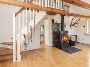 A staircase with white railings and wooden beams, a fireplace with a black mantel, and a deer skull mounted on the wall. - 12 Person Holiday Home in Thisted (Frøstrup)